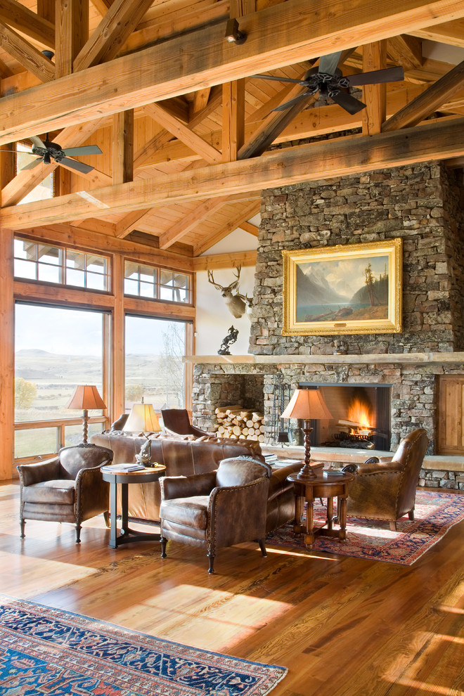 rustic cottage home wood beams big stone rock fireplace leather sofa chairs persian carpet deet antlers on wall better decorating bible blog inside home