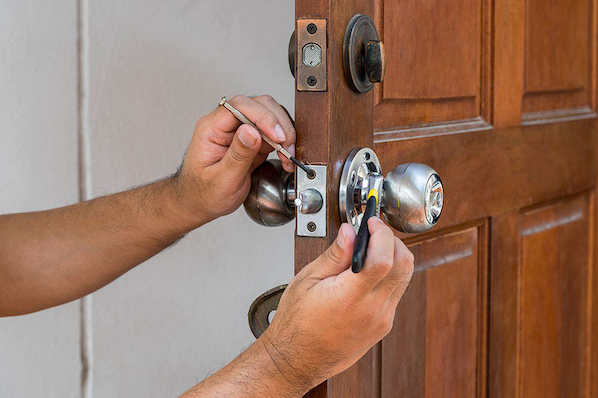 Locksmith fixing lock on door.