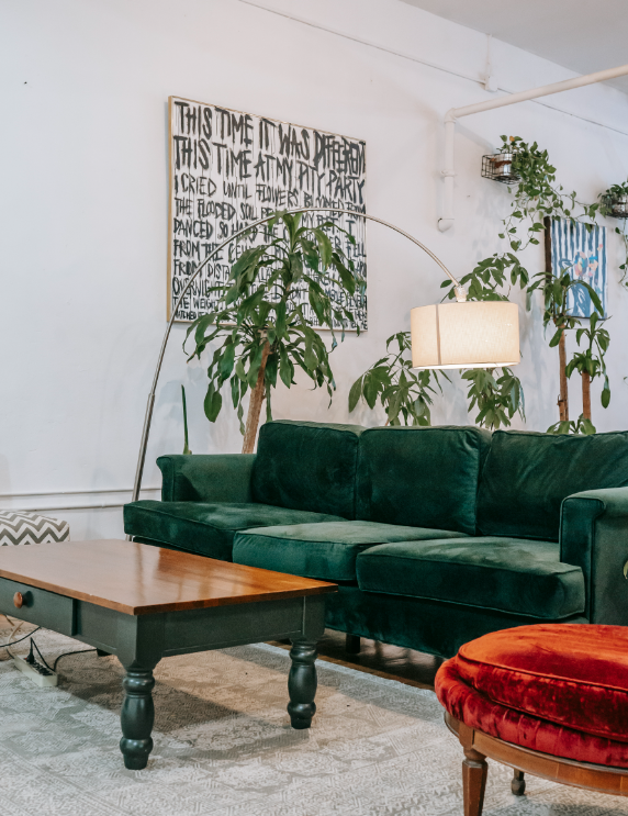 Green velvet sofa in living room with abstract artwork.