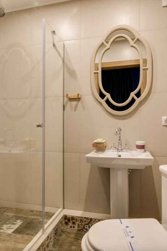 Beige tiled bathroom decor with Moroccan style mirror. 
