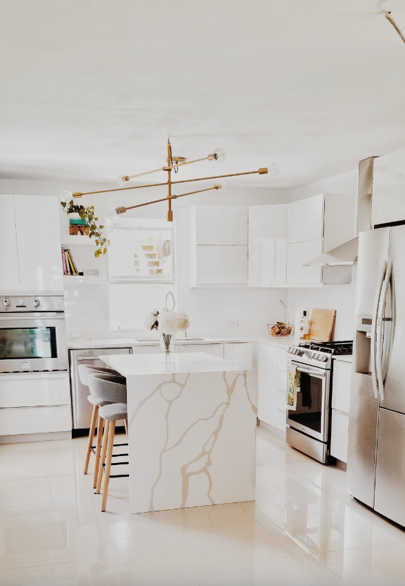 White kitchen with white Calcutta marble and gold chandelier.